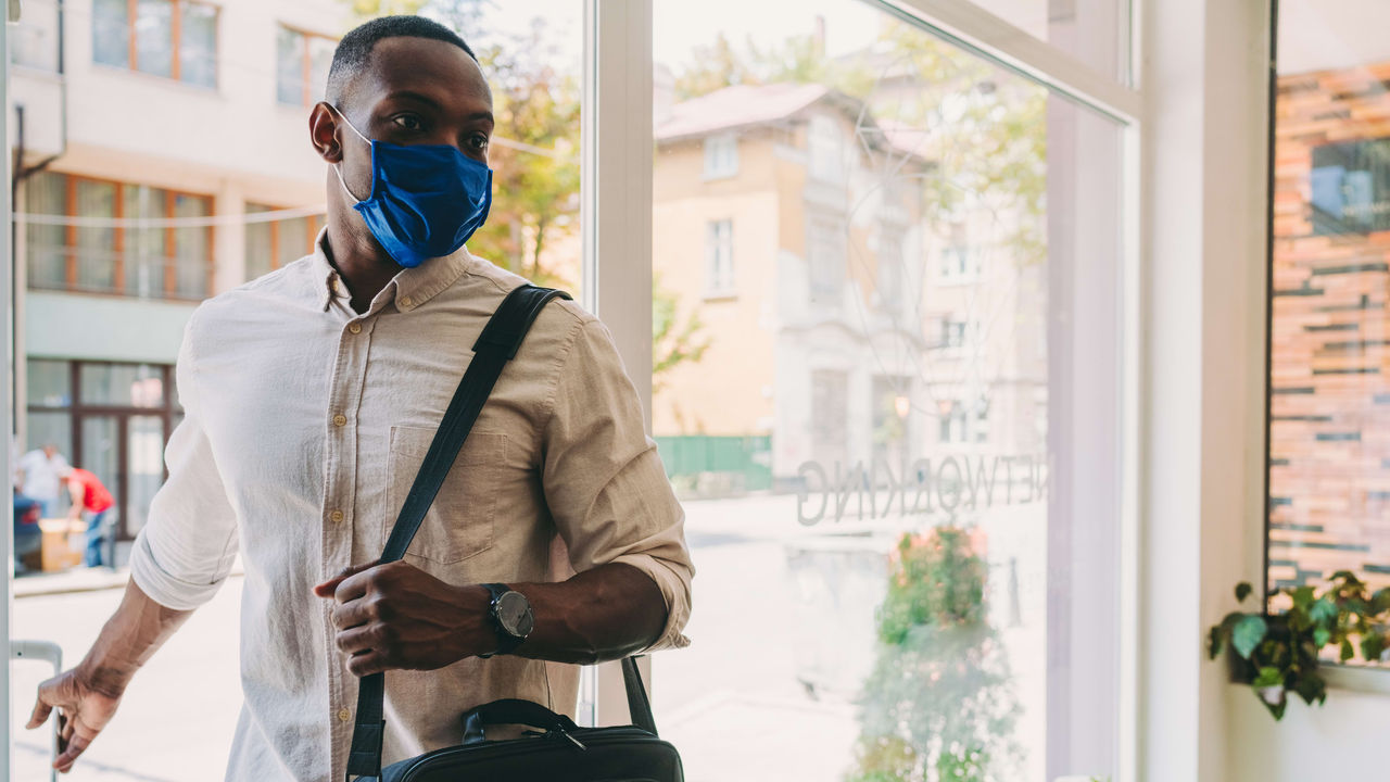 A man wearing a face mask and carrying a backpack.