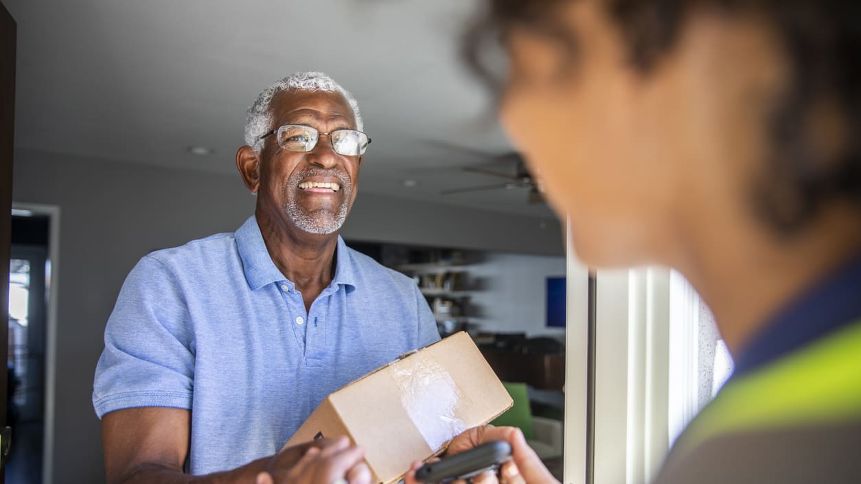 An older man handing a package to a woman.