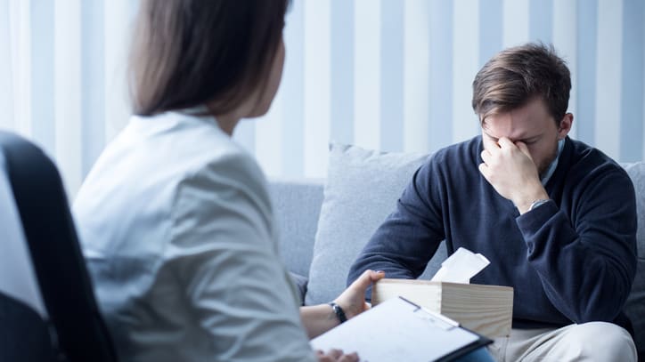 A man is sitting on a couch while a woman is sitting next to him.