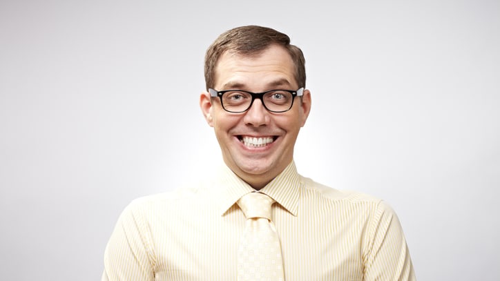 A smiling man wearing glasses and a tie.