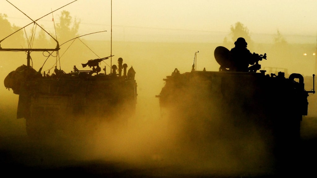 Israeli army vehicles on a dusty road.