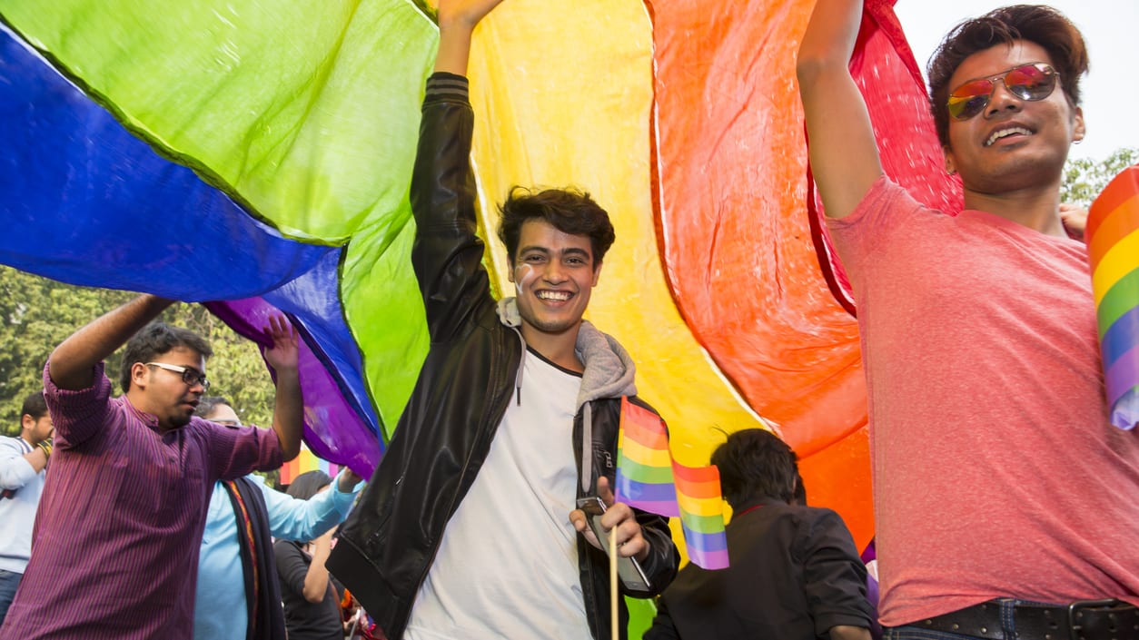 A group of people holding up a rainbow flag.