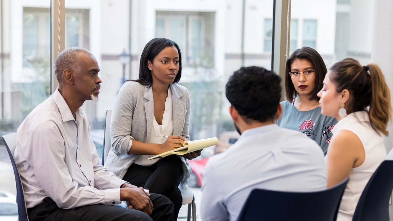 A group of people sitting around a table in an office.