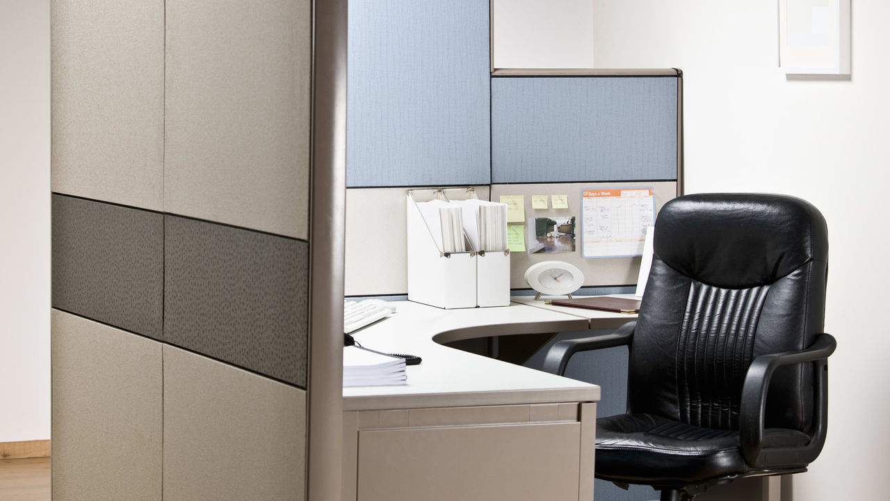 An office cubicle with a black chair and desk.