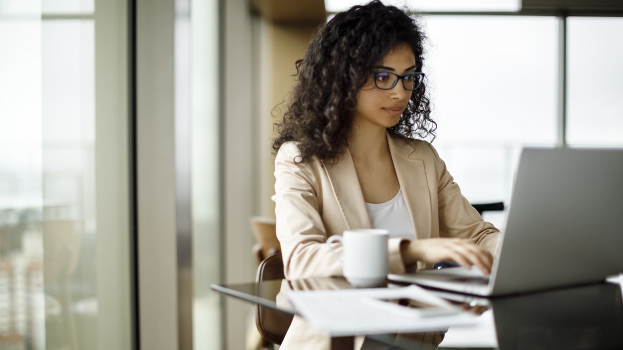 A business woman working on a laptop in an office.