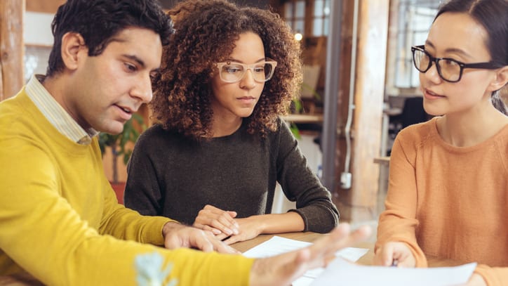 A group of people sitting around a table looking at papers.