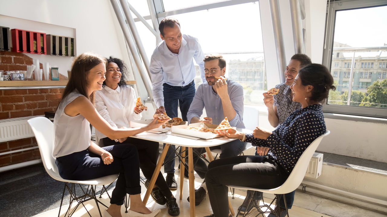 A group of people sitting around a table eating pizza.