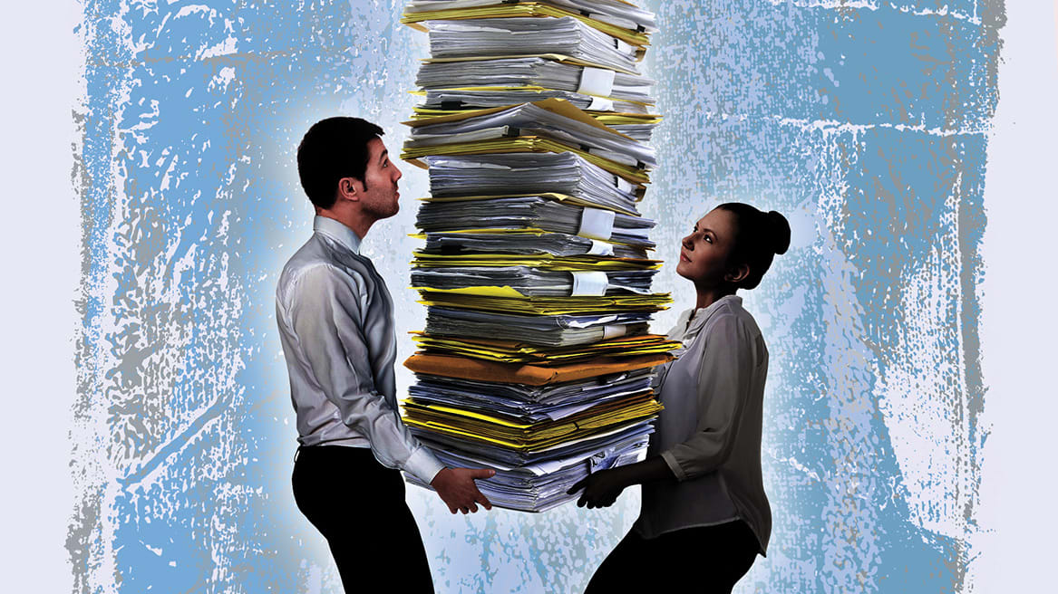 A man and a woman carrying a stack of documents.