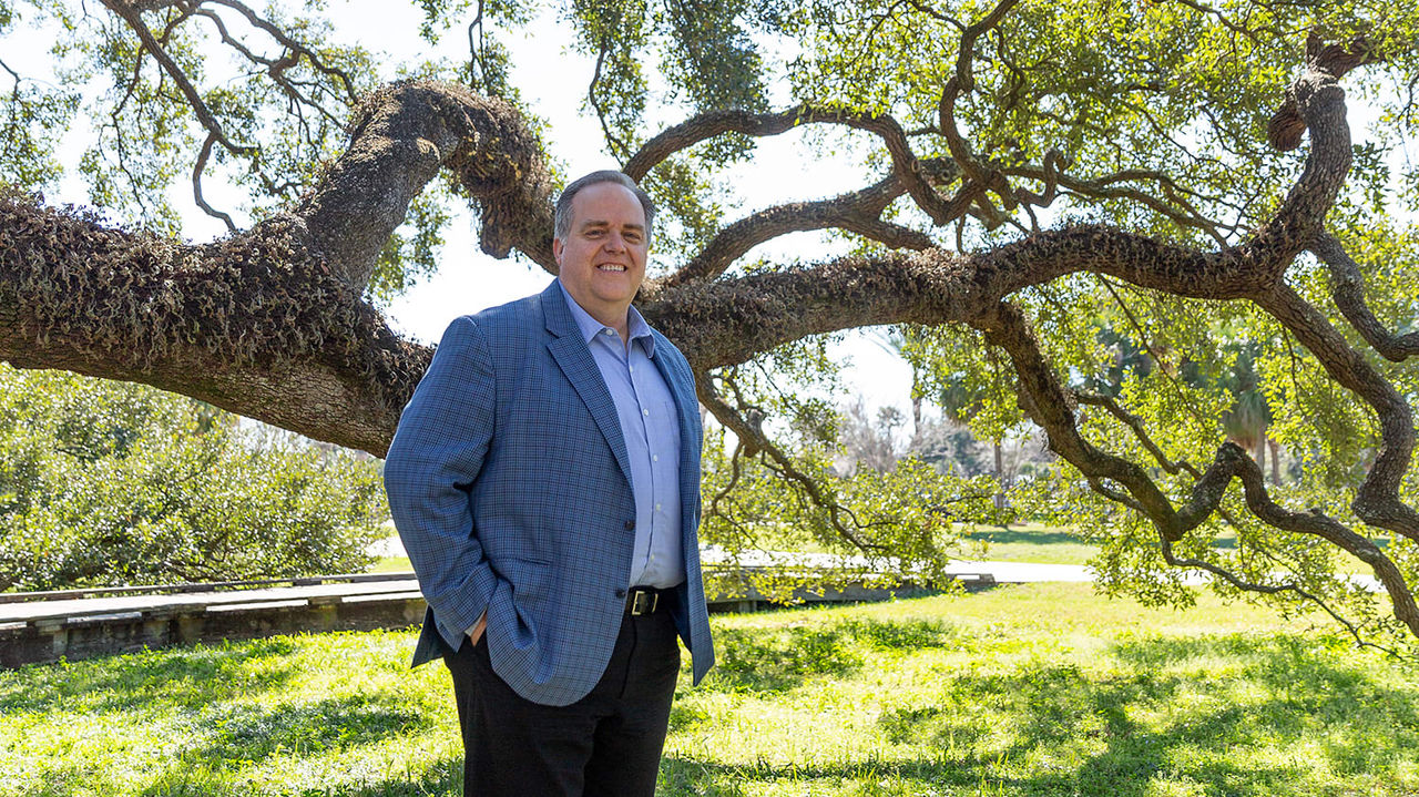 A man standing in front of a large tree.