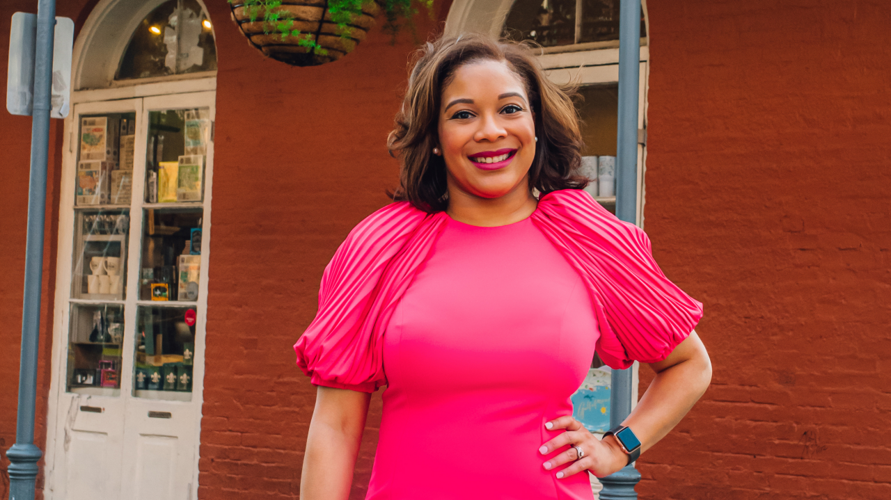 A woman in a pink dress standing in front of a building.