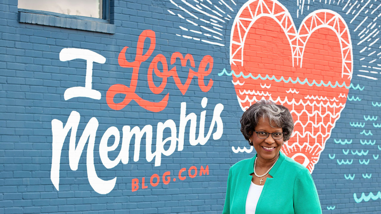 A woman standing in front of a mural that says i love memphis.