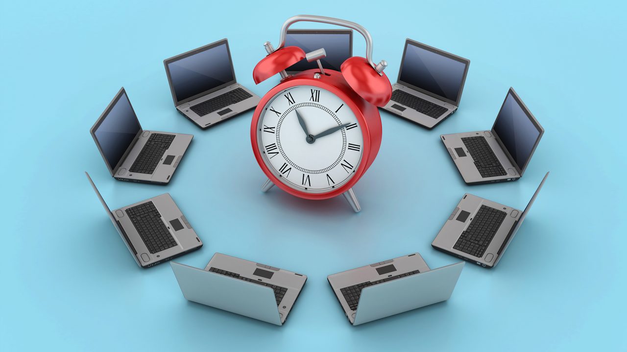 Laptops surrounding an alarm clock