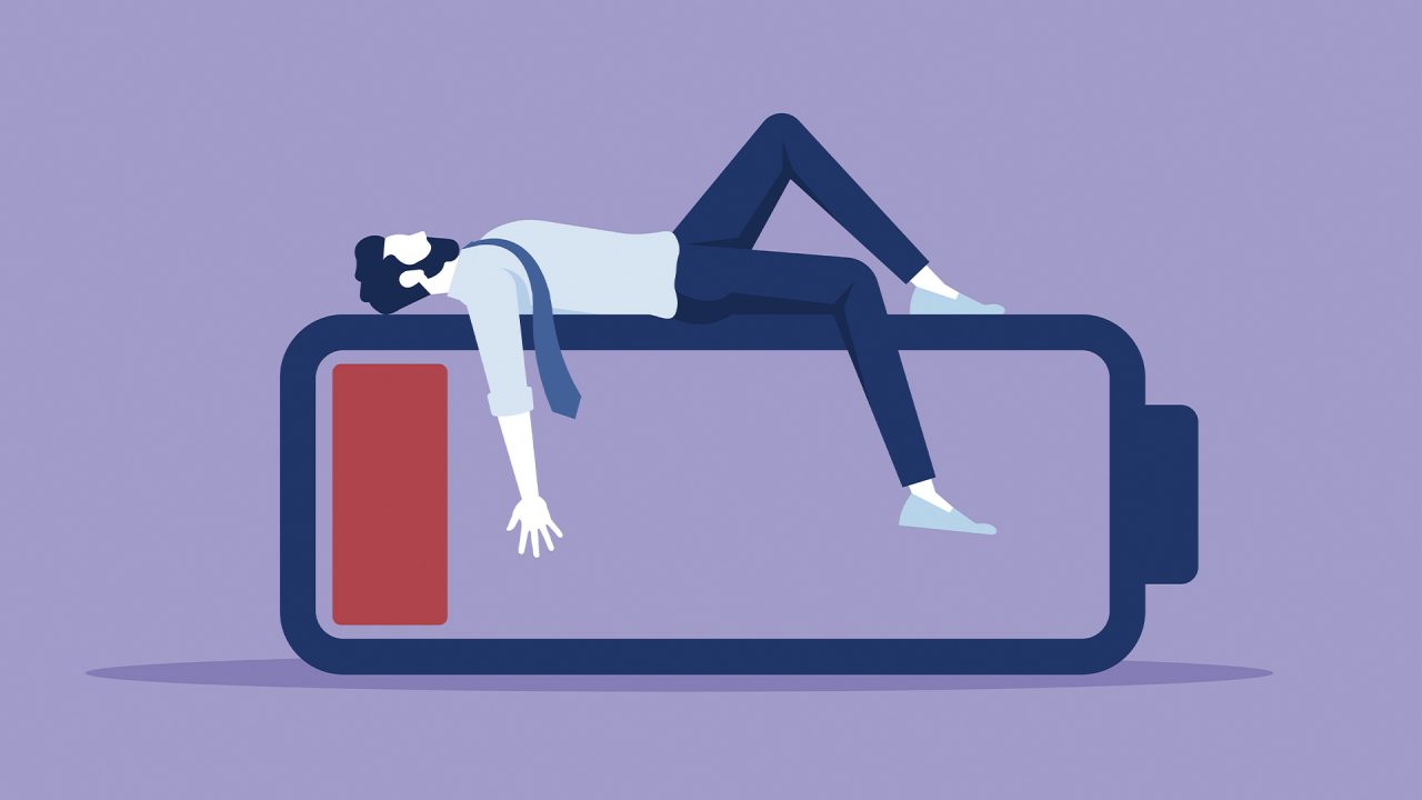 An exhausted employee lays on top of a large "low battery" symbol.