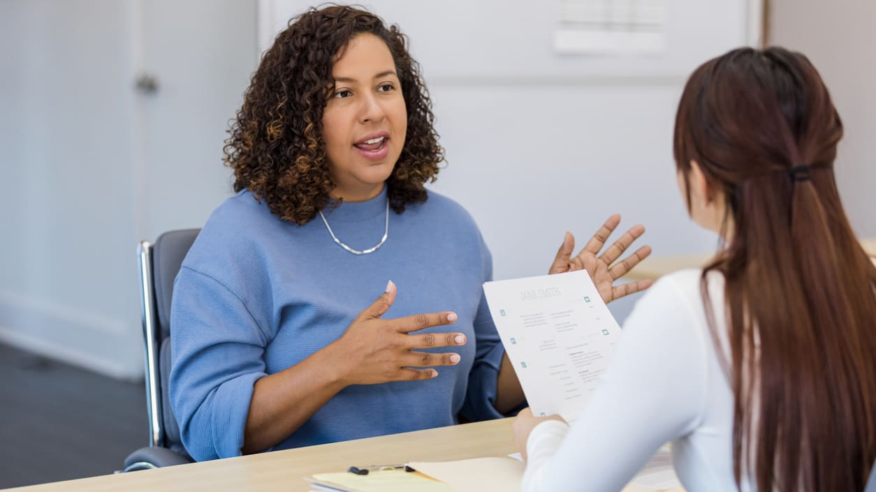 A woman talking to a woman in an office.