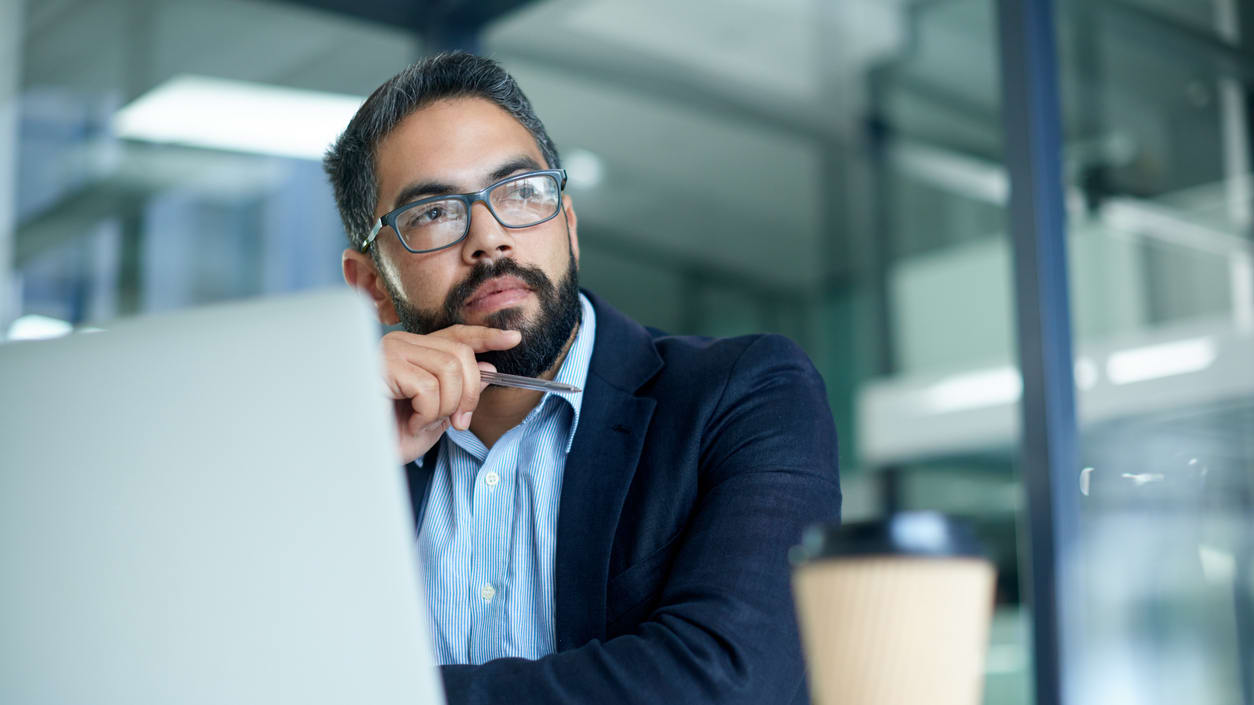 A man with glasses and a beard sitting in front of a laptop.