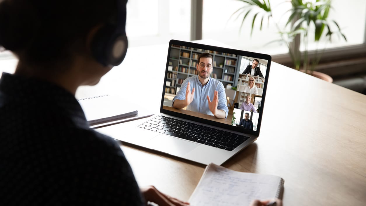 A woman is on a video call with a group of people on a laptop.