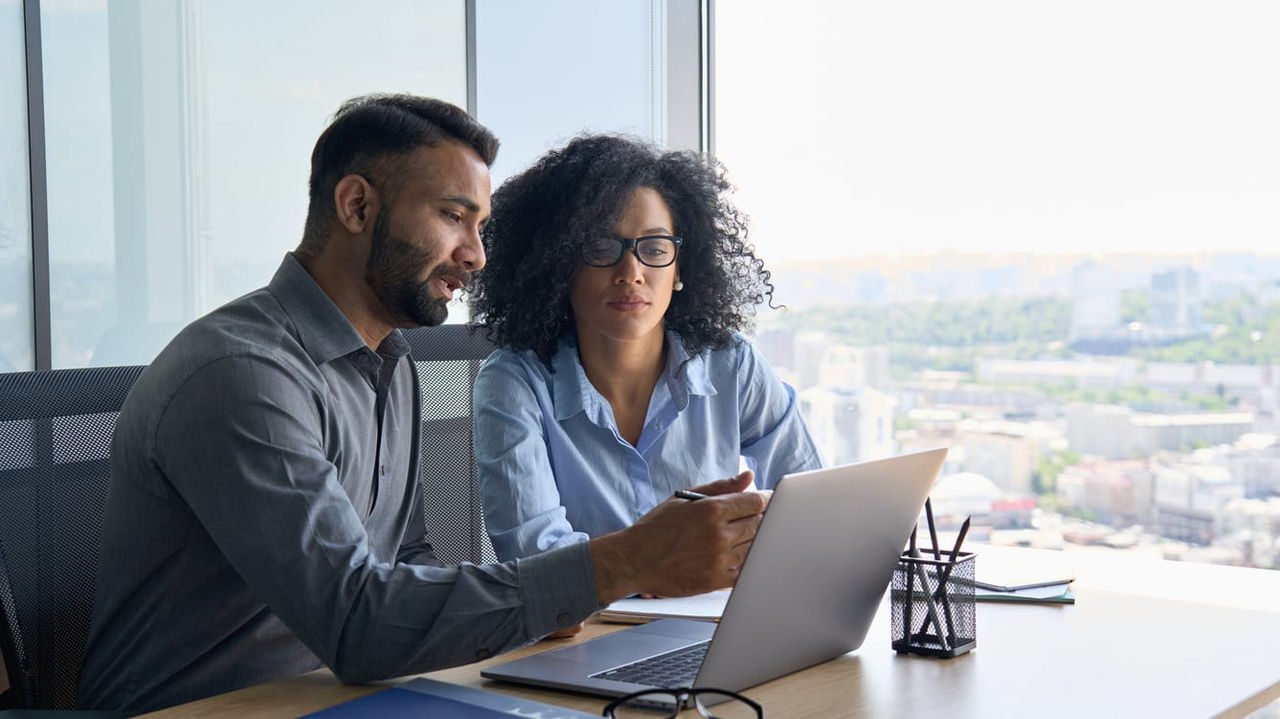 Two business people working on a laptop in an office.