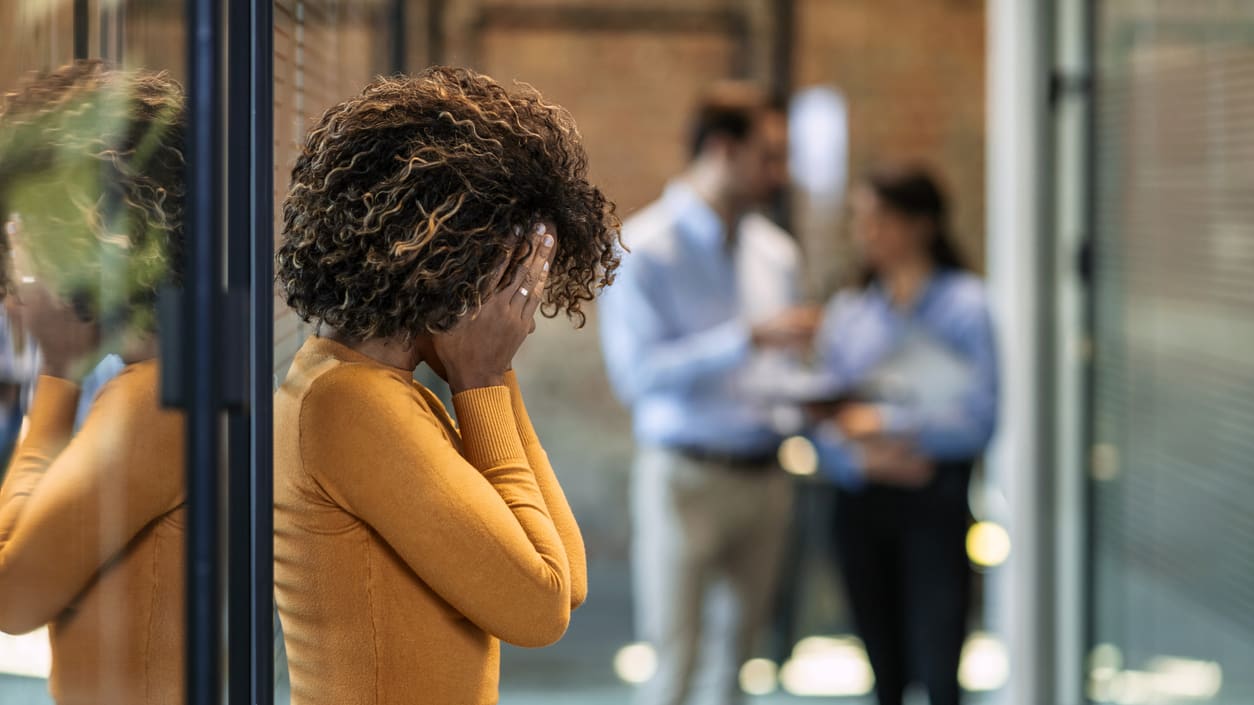 A woman is standing in front of a glass door in an office.