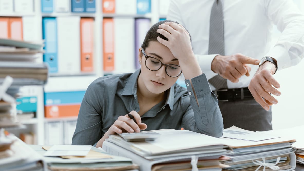 A man and a woman sitting in front of a pile of papers.