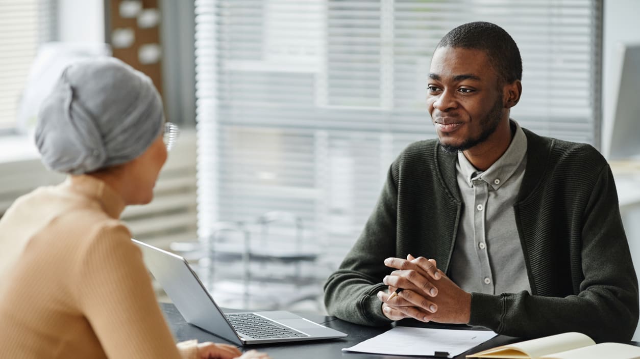 A man and woman talking at a desk in an office.