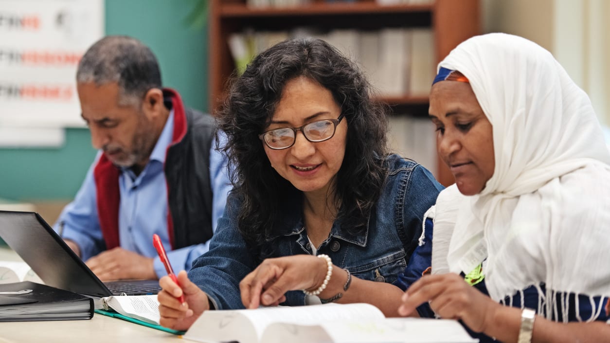 A group of people sitting at a table in a library.