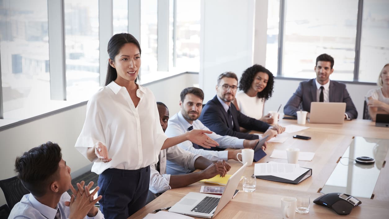 A woman is giving a presentation to a group of people at a conference table.