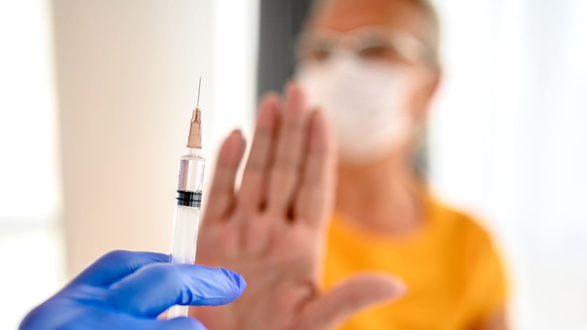 A woman is holding a syringe and giving it to another person who is holding their hand up.