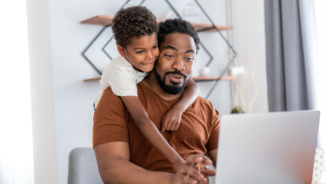 A man and his son using a laptop at home.