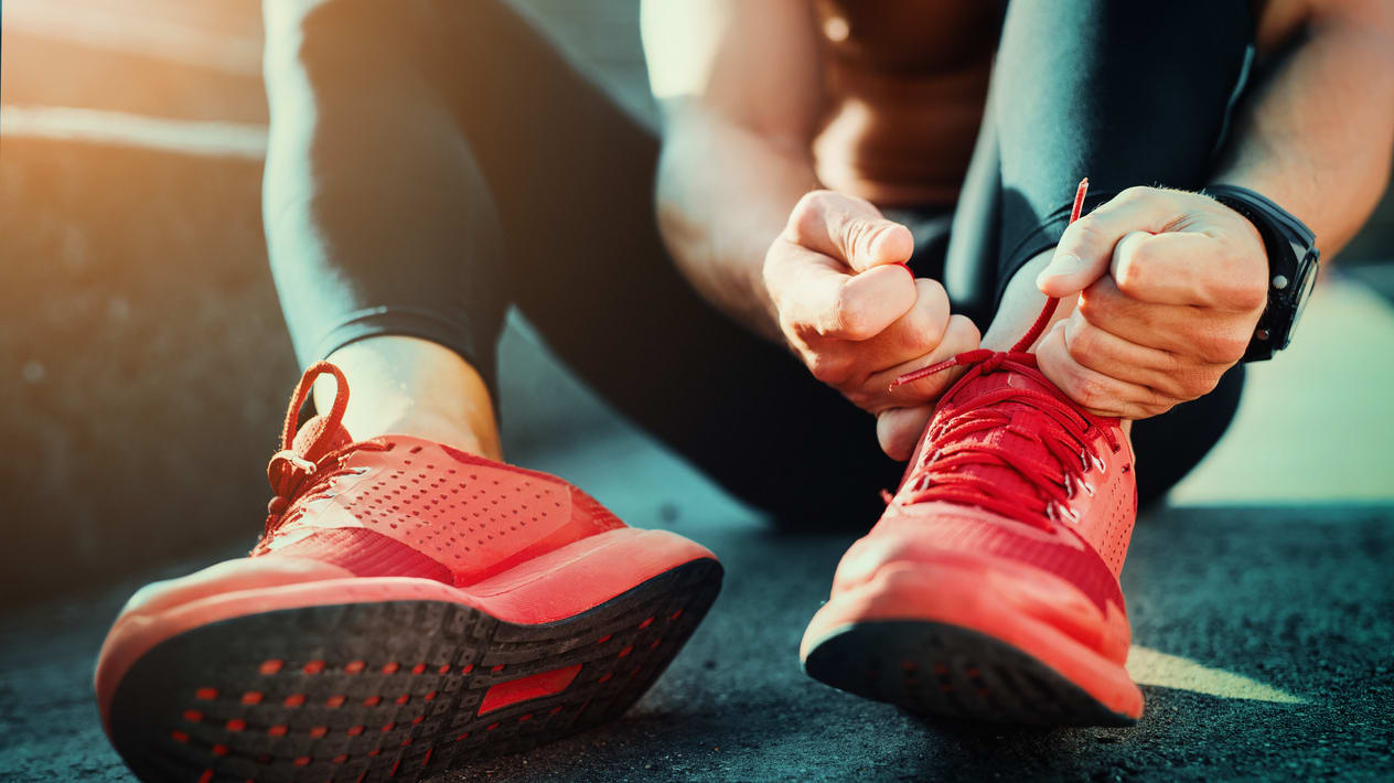 A man is tying his red running shoes.