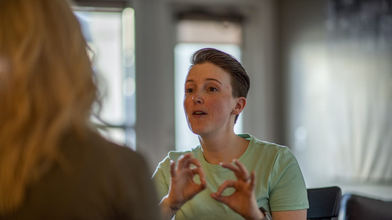 A woman sitting at a table talking to another woman.