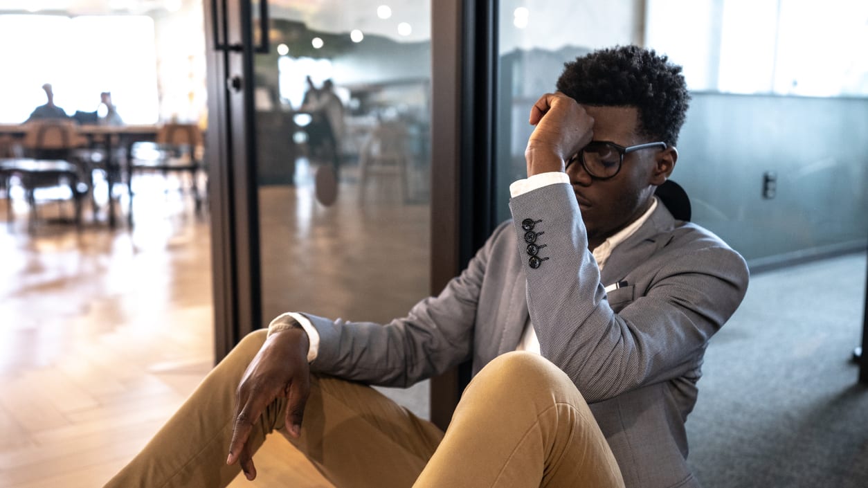 A businessman sitting on the floor in an office.