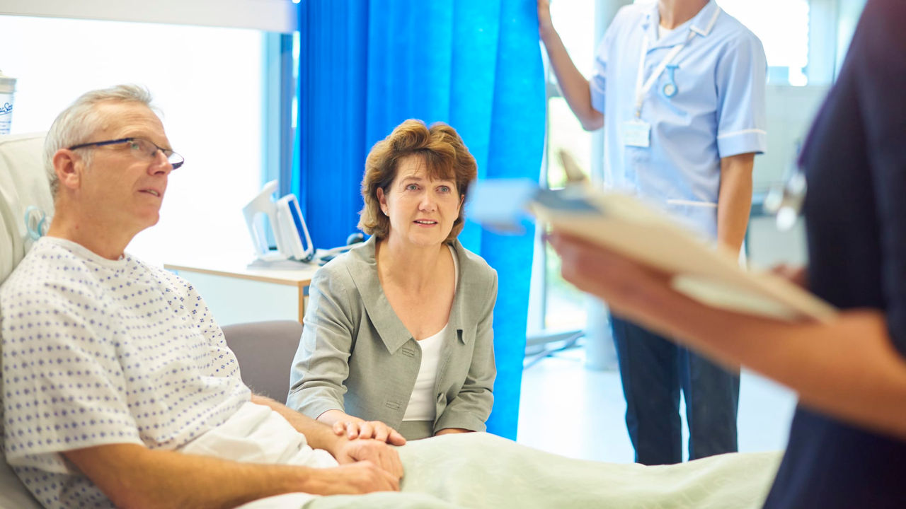A nurse is talking to a patient in a hospital room.
