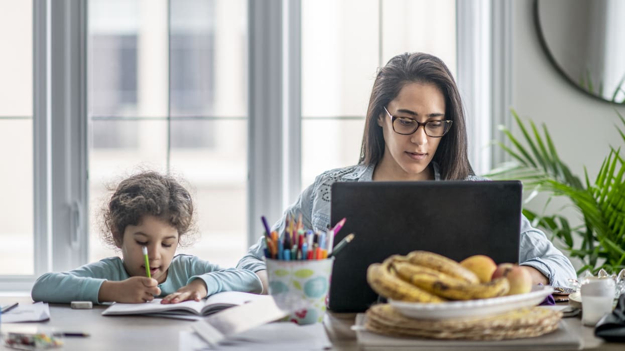 A woman and child working on a laptop at home.