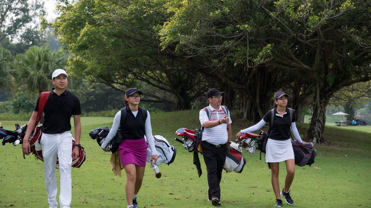 A group of people walking on a golf course.