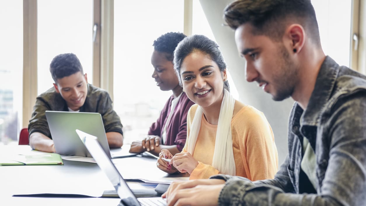 A group of people sitting around a table working on laptops.
