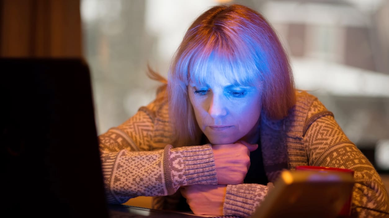 A woman looking at her laptop at night.