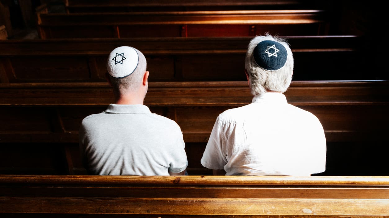 Two men sitting in a pew in a church.