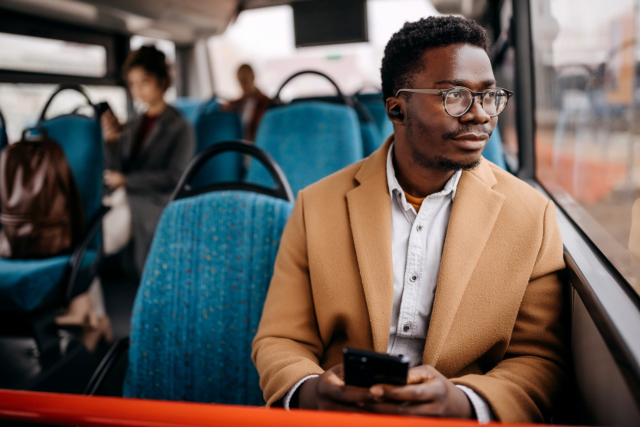 Black man holding phone while sitting on a bus