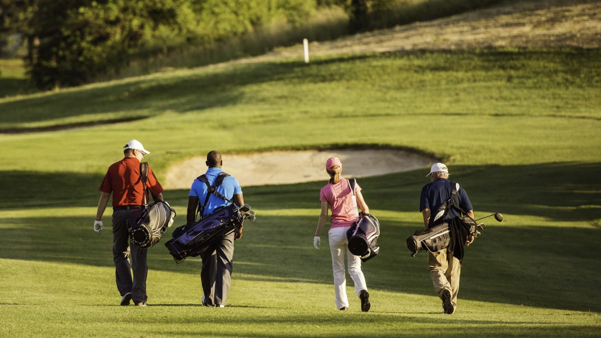 A group of people walking on a golf course.