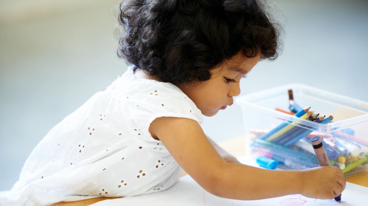 A little girl is drawing on a piece of paper.