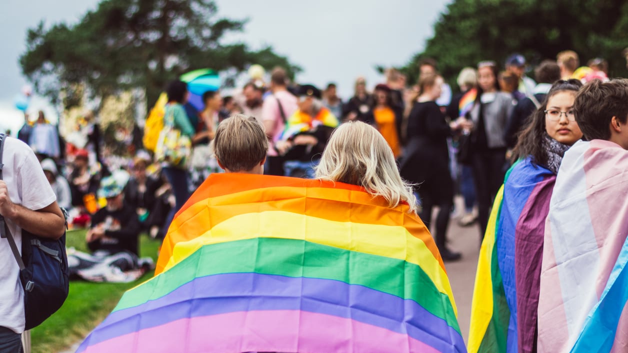 A group of people holding rainbow flags in front of a crowd.