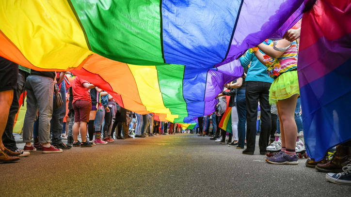 A group of people holding a rainbow flag.