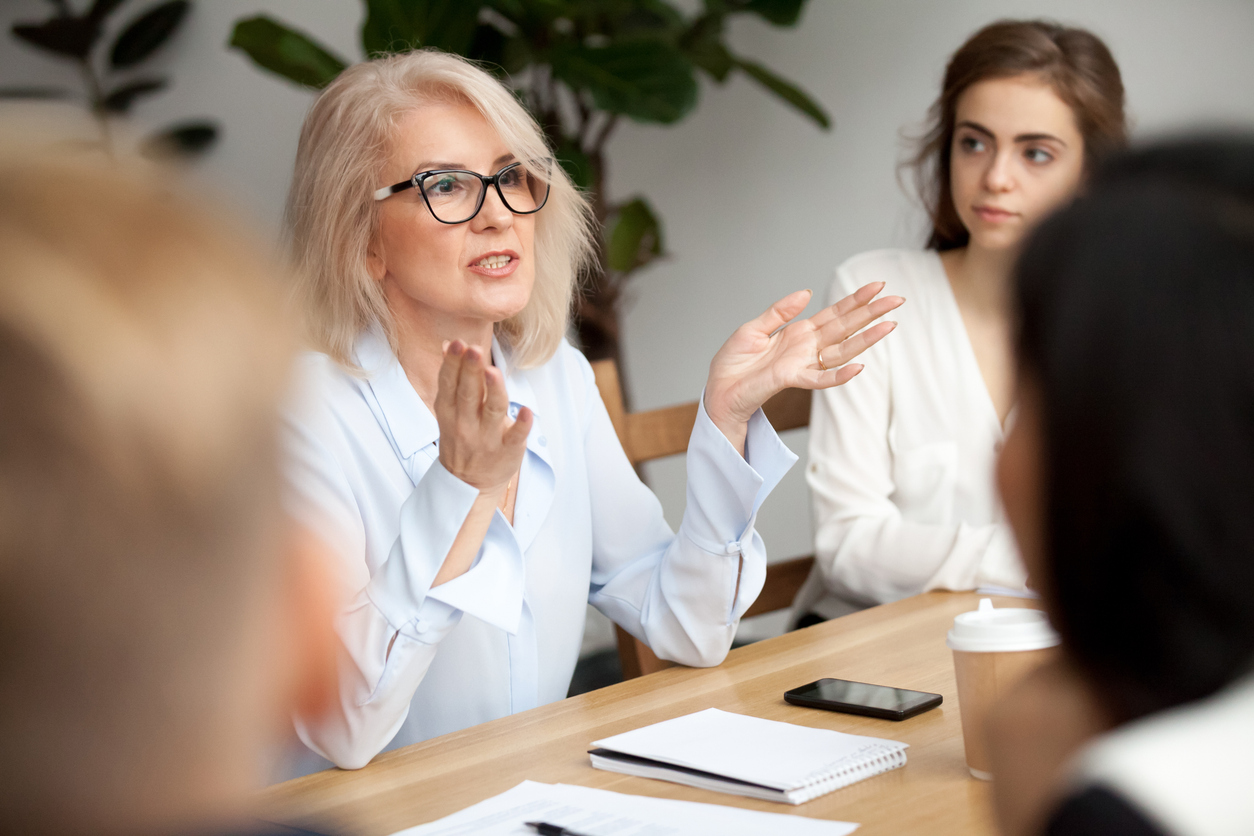 Older woman with glasses speaks during meeting