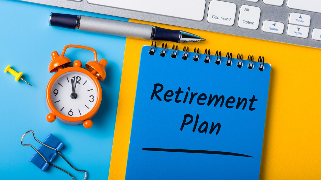 A notepad with the word retirement plan on it next to a keyboard.