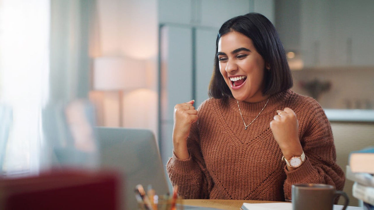 A woman is sitting at a desk with a laptop in front of her.