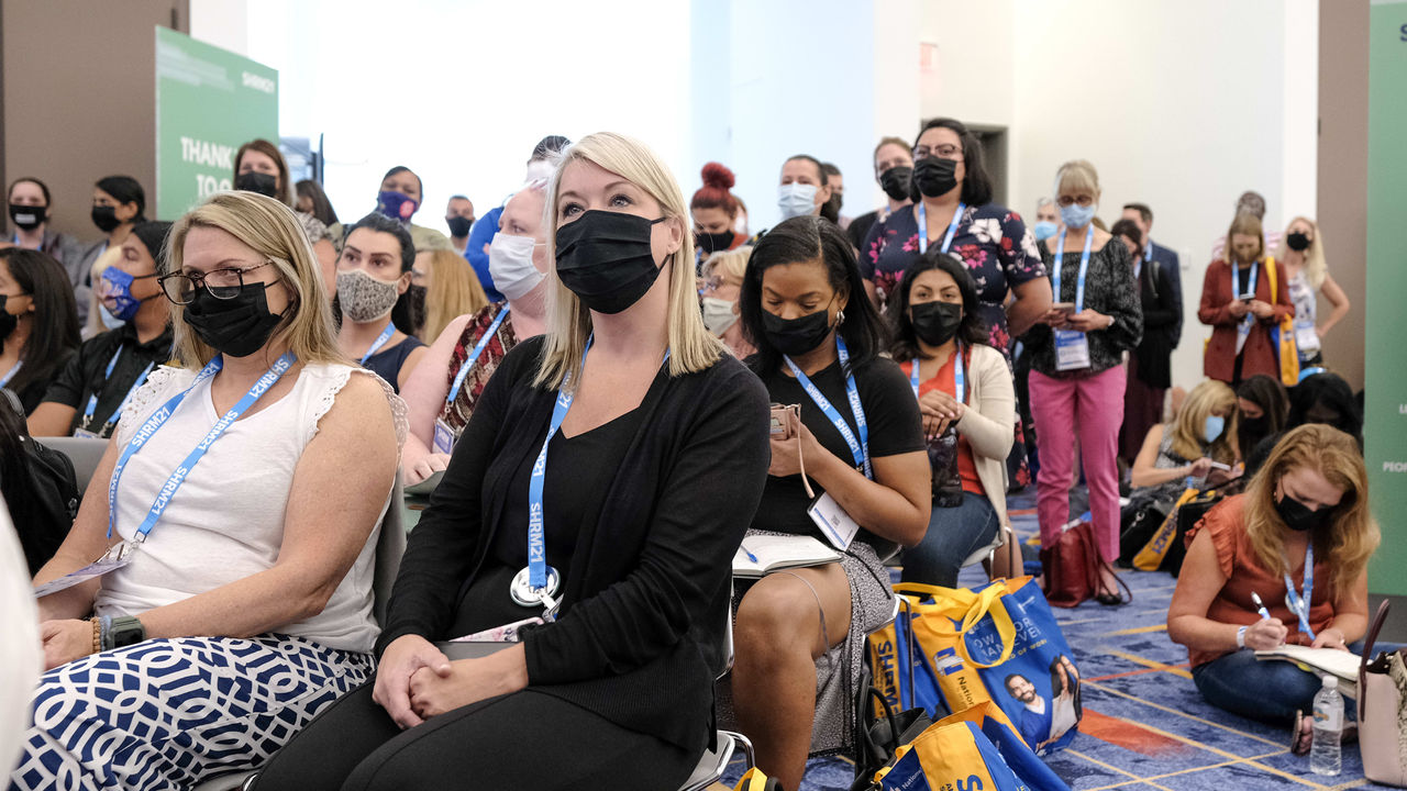 A group of people wearing face masks at a conference.