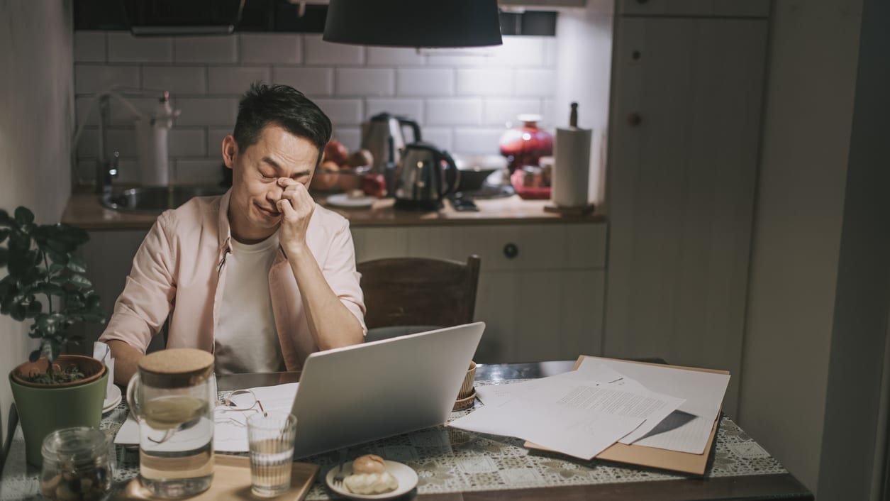 A man sitting at a table with a laptop in front of him.