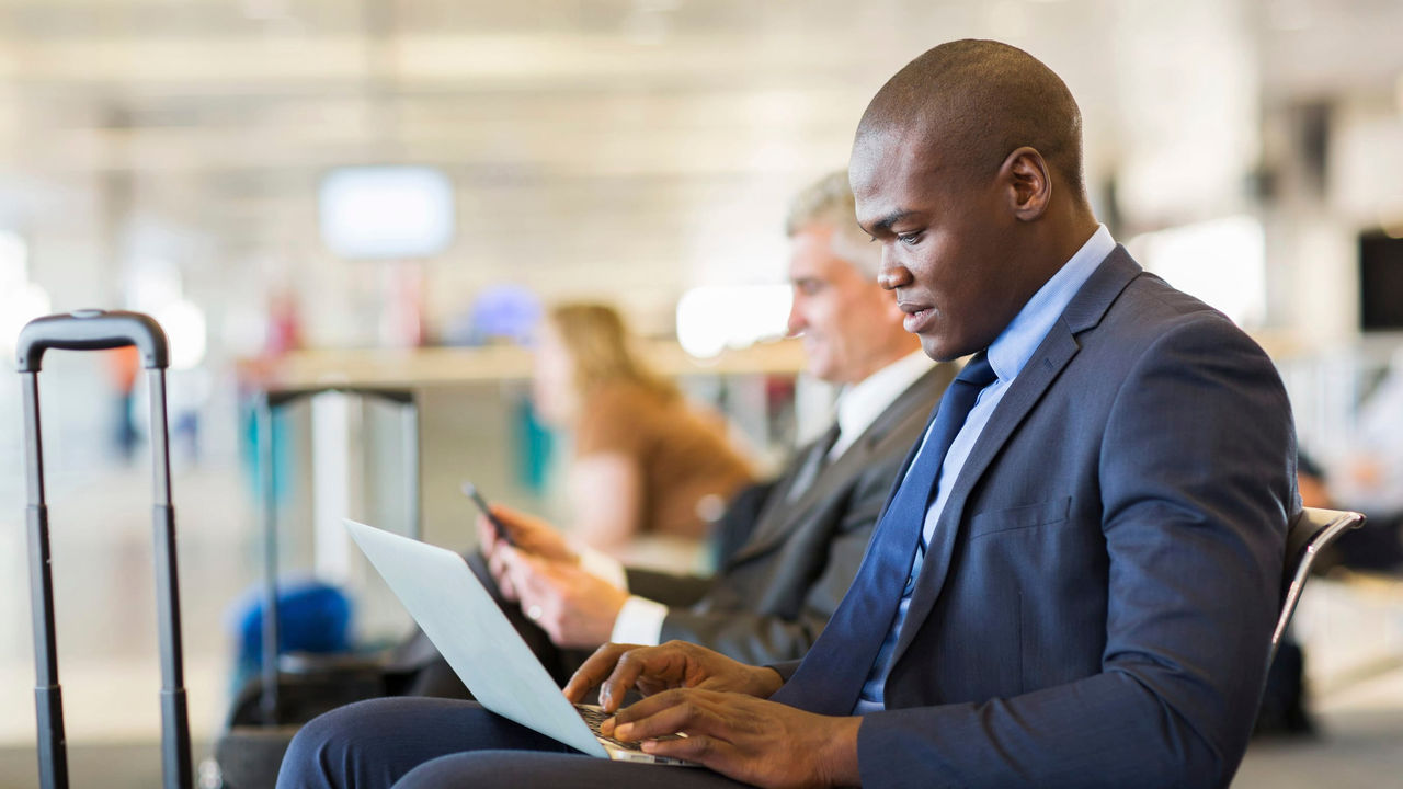 A man in a suit is using a laptop in an airport.