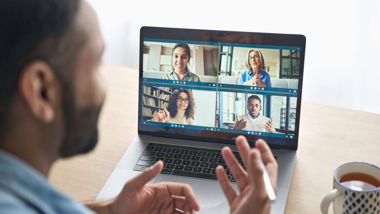 A man is using a laptop to do a video conference.