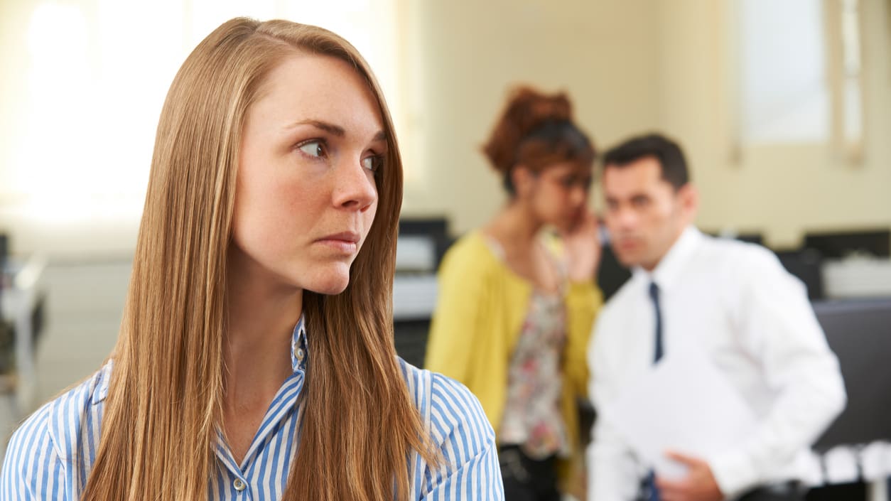A woman is standing in front of a group of people in an office.
